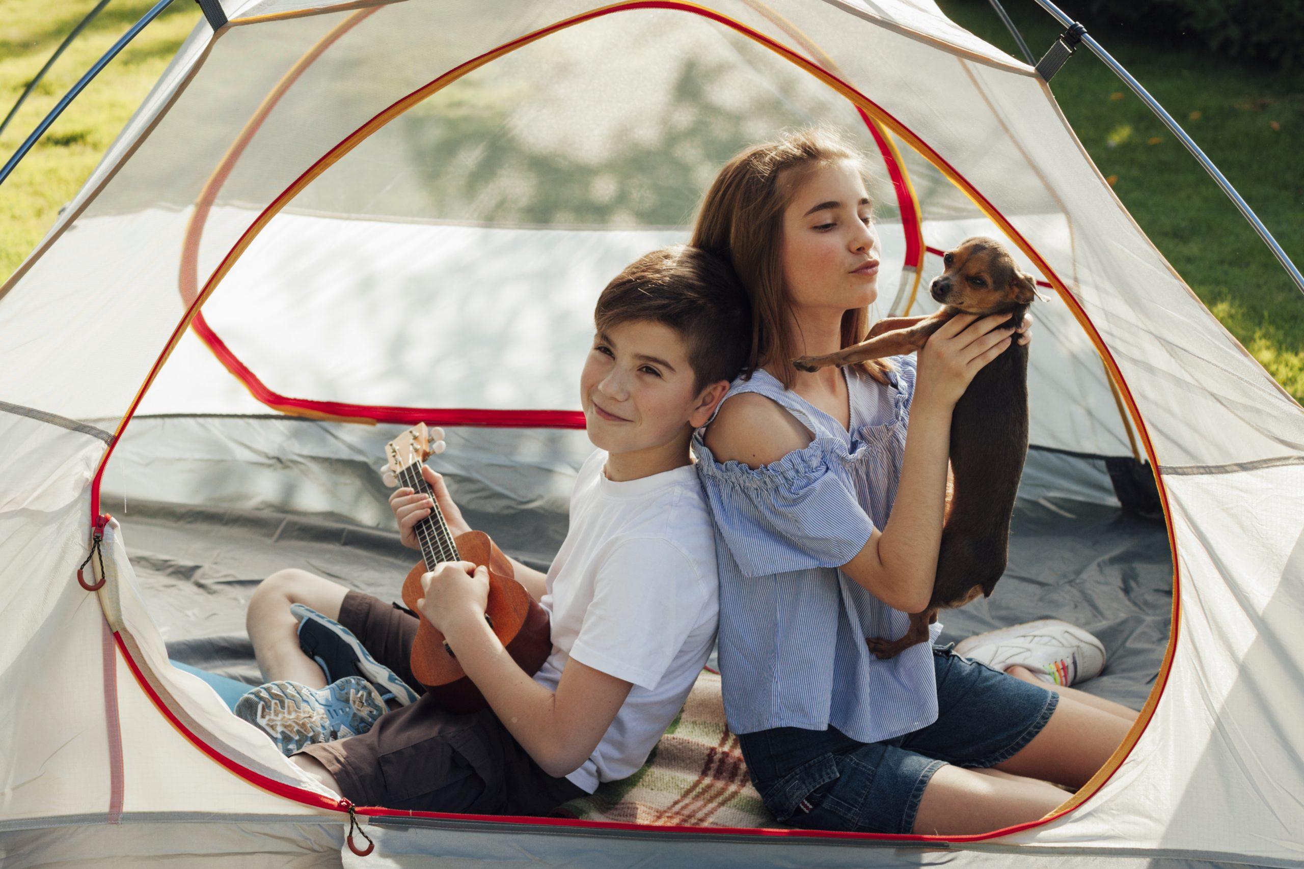 portrait-of-boy-and-girl-sitting-in-tent-with-holding-dog-and-ukulele